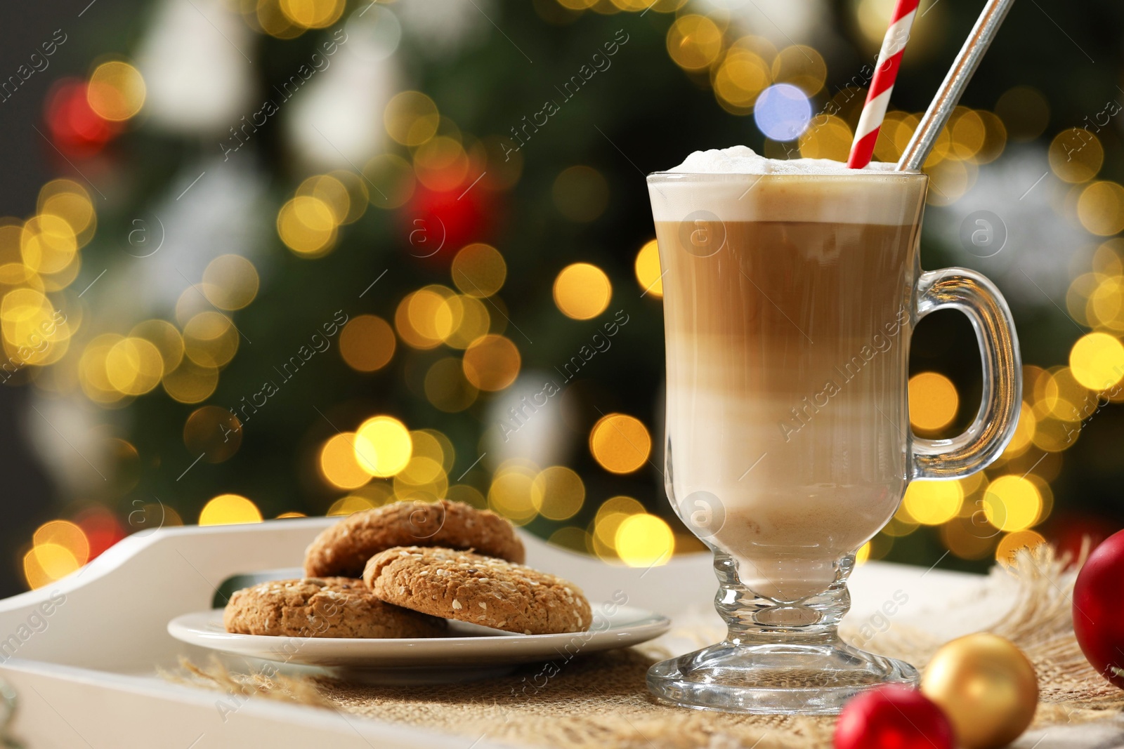 Photo of Aromatic coffee in glass and tasty cookies on tray against blurred Christmas lights, bokeh effect