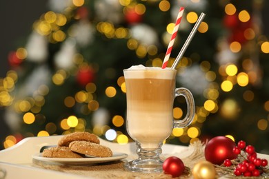 Photo of Aromatic coffee in glass, tasty cookies and decor on tray against blurred Christmas lights, bokeh effect