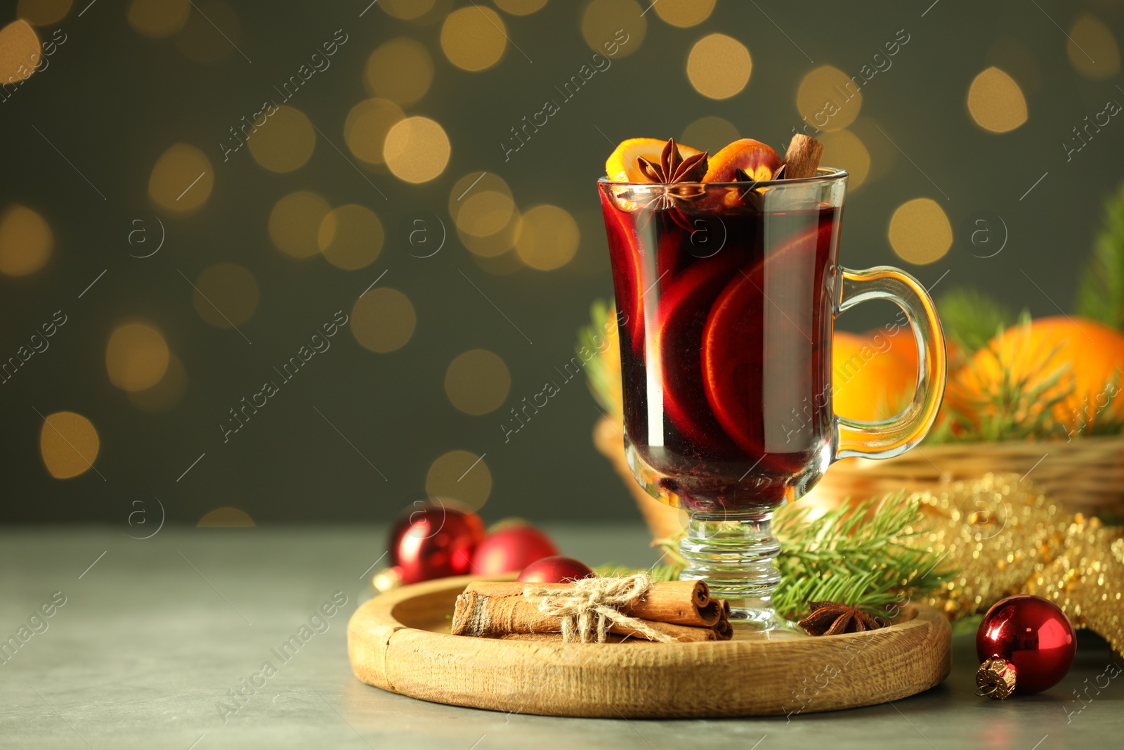 Photo of Tasty mulled wine, spices and Christmas decor on light table against blurred lights, closeup. Space for text