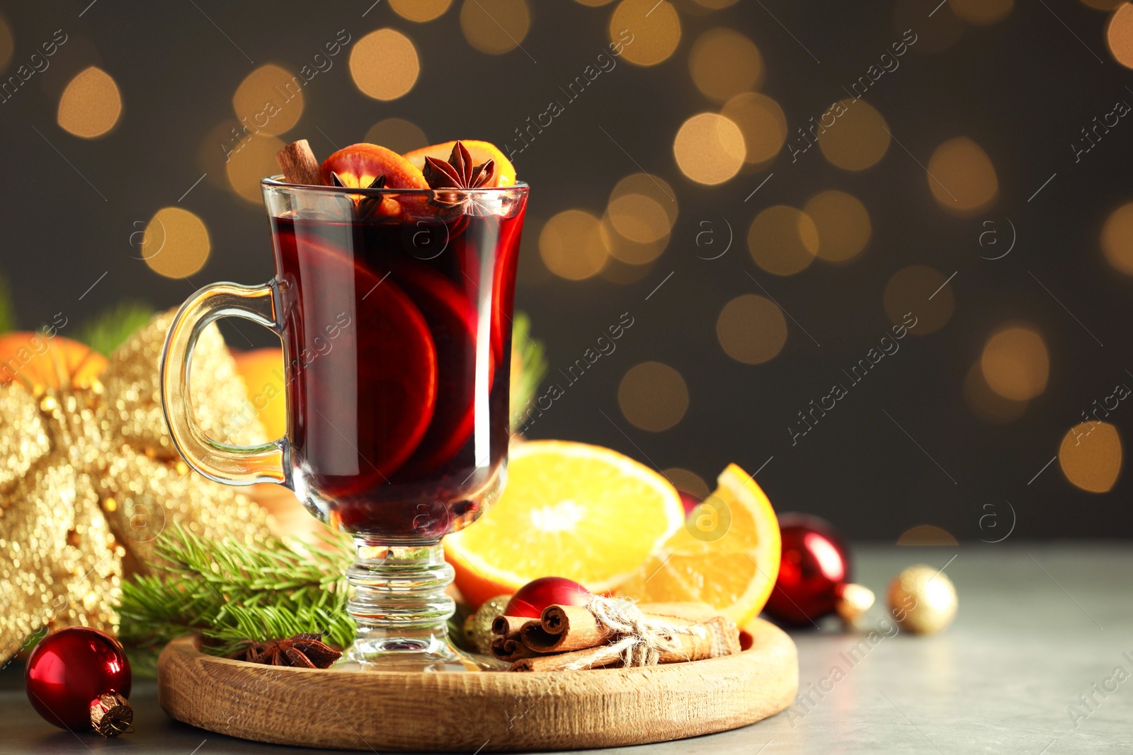 Photo of Tasty mulled wine, spices and Christmas decor on light table against blurred lights, closeup. Space for text