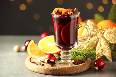 Photo of Tasty mulled wine, spices and Christmas decor on light table against blurred lights, closeup