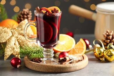 Photo of Tasty mulled wine, spices and Christmas decor on light table against blurred lights, closeup