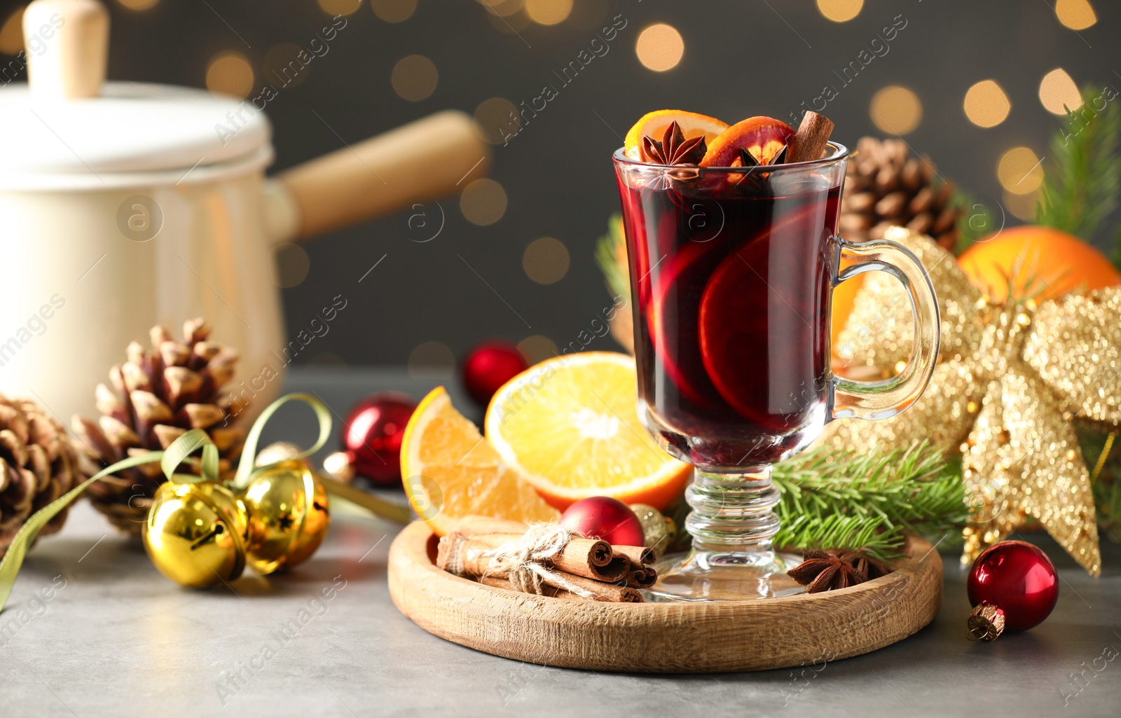 Photo of Tasty mulled wine, spices and Christmas decor on light table against blurred lights, closeup