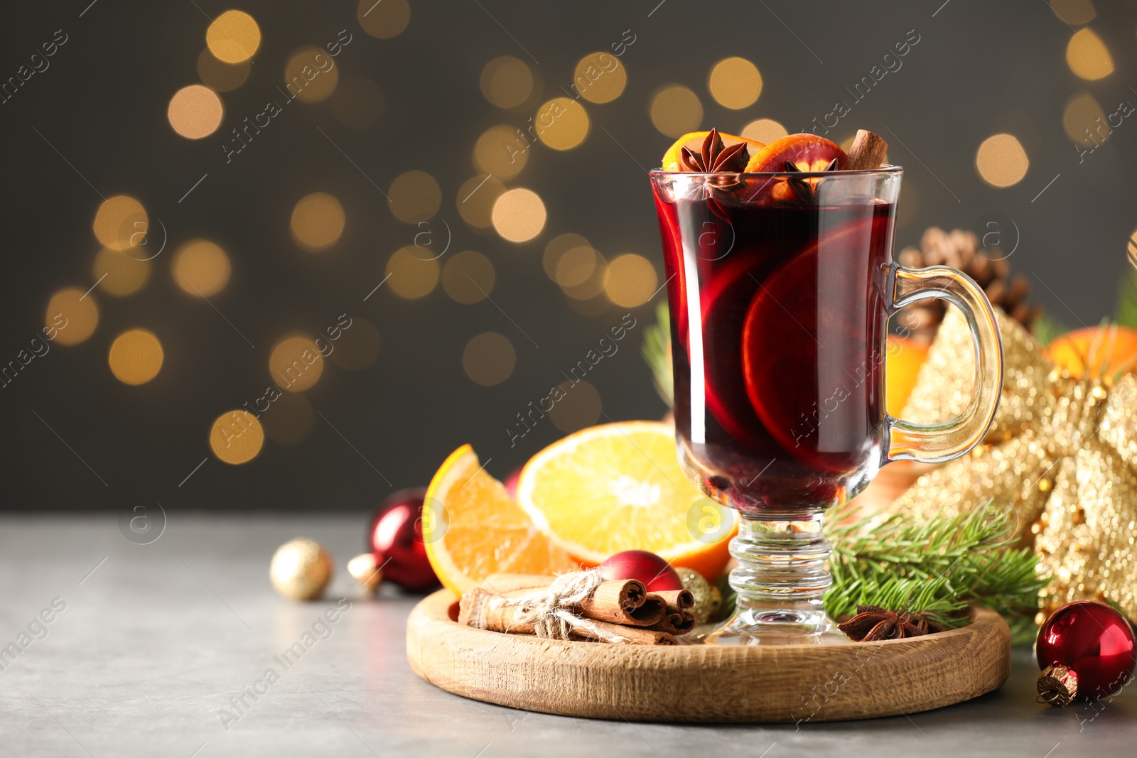 Photo of Tasty mulled wine, spices and Christmas decor on light table against blurred lights, closeup. Space for text