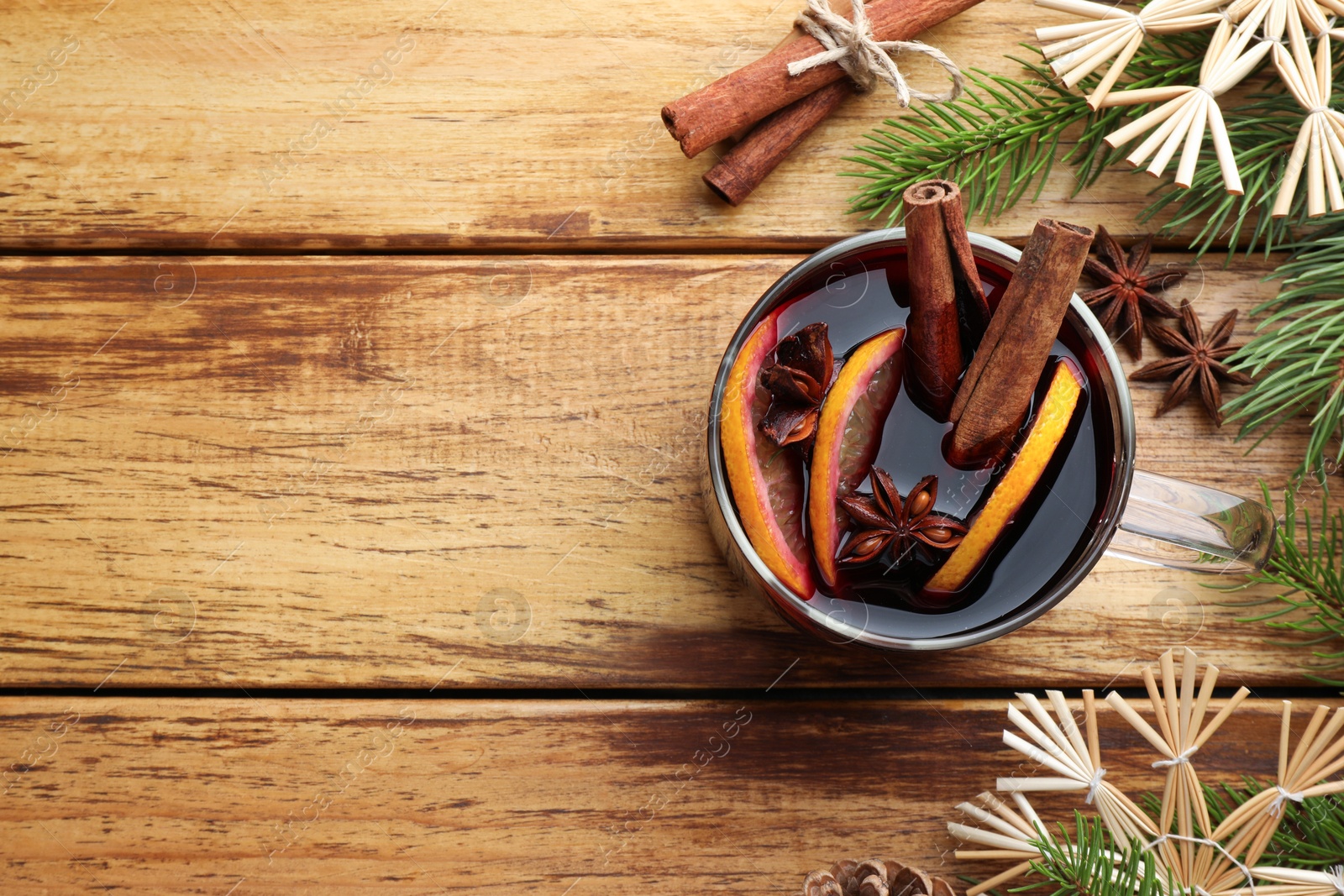 Photo of Tasty mulled wine with spices, orange and Christmas decor on wooden table, flat lay. Space for text