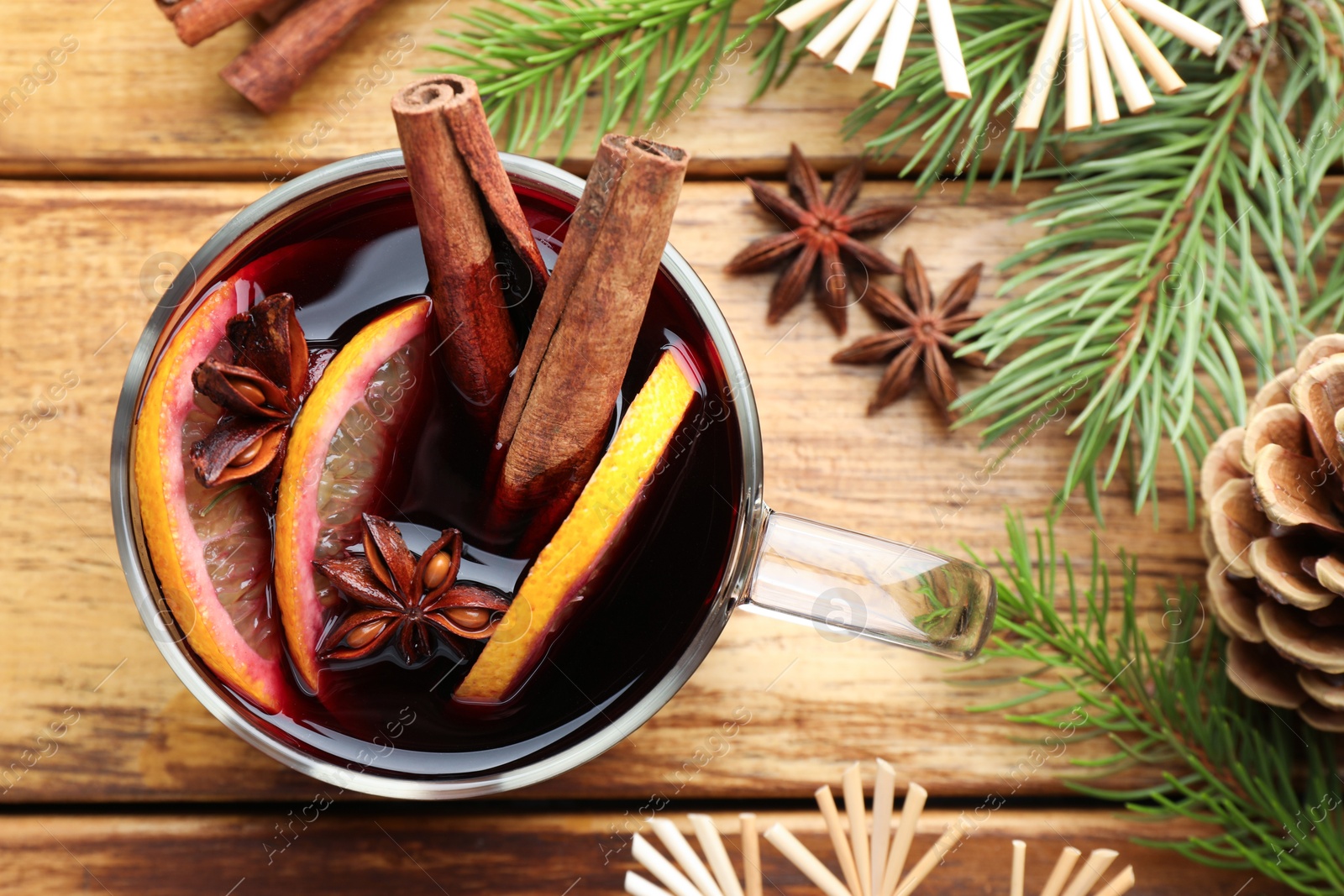 Photo of Tasty mulled wine with spices, orange slices and Christmas decor on wooden table, flat lay