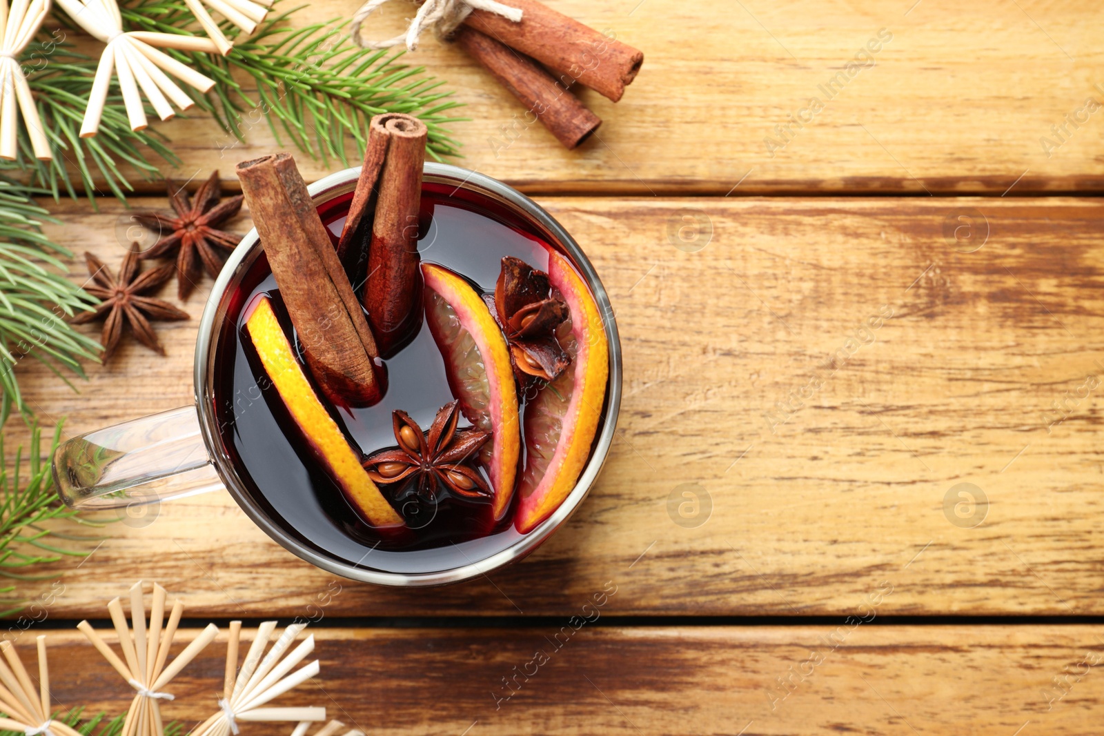 Photo of Tasty mulled wine with spices, orange and Christmas decor on wooden table, flat lay. Space for text