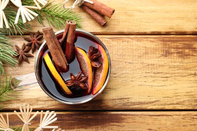 Photo of Tasty mulled wine with spices, orange and Christmas decor on wooden table, flat lay. Space for text