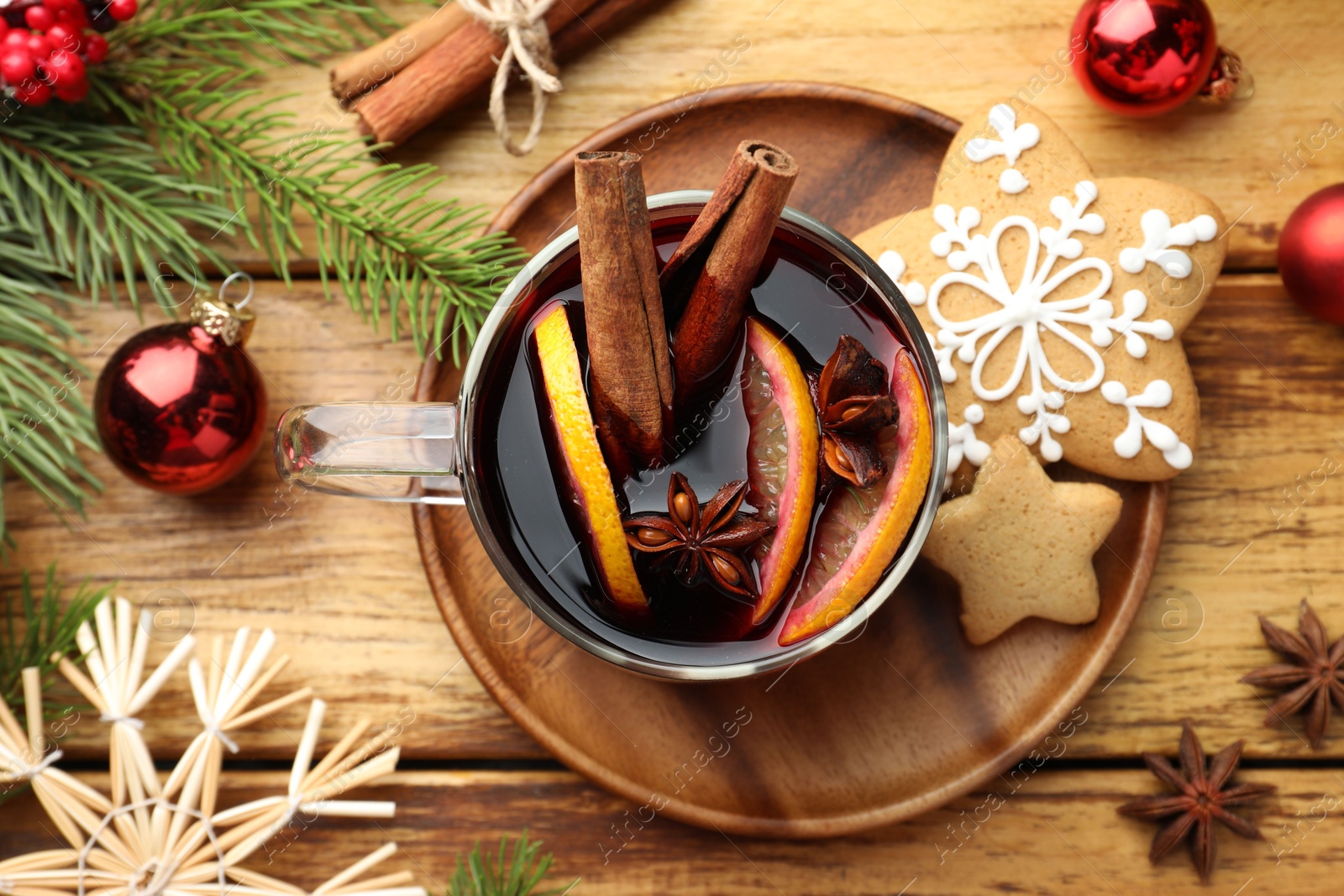 Photo of Tasty mulled wine with spices, cookies and Christmas decor on wooden table, flat lay