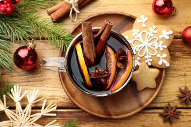 Photo of Tasty mulled wine with spices, cookies and Christmas decor on wooden table, flat lay