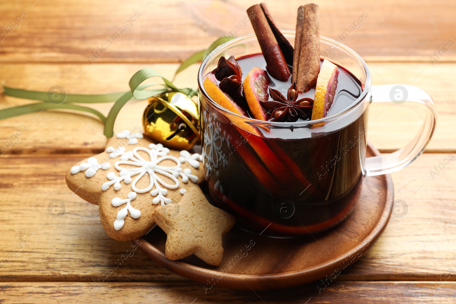 Photo of Tasty mulled wine with spices, cookies and Christmas decor on wooden table, closeup