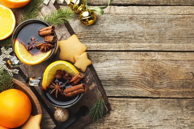 Photo of Tasty mulled wine with spices, orange, cookies and Christmas decor on wooden table, flat lay. Space for text