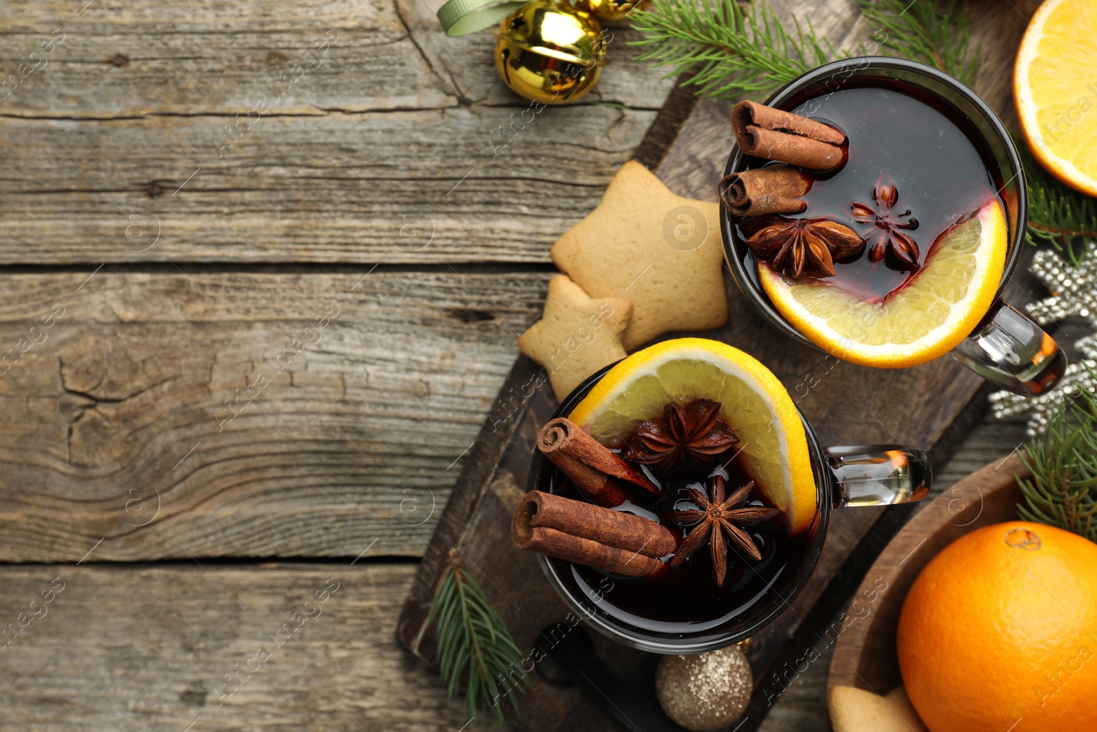 Photo of Tasty mulled wine with spices, orange, cookies and Christmas decor on wooden table, flat lay. Space for text