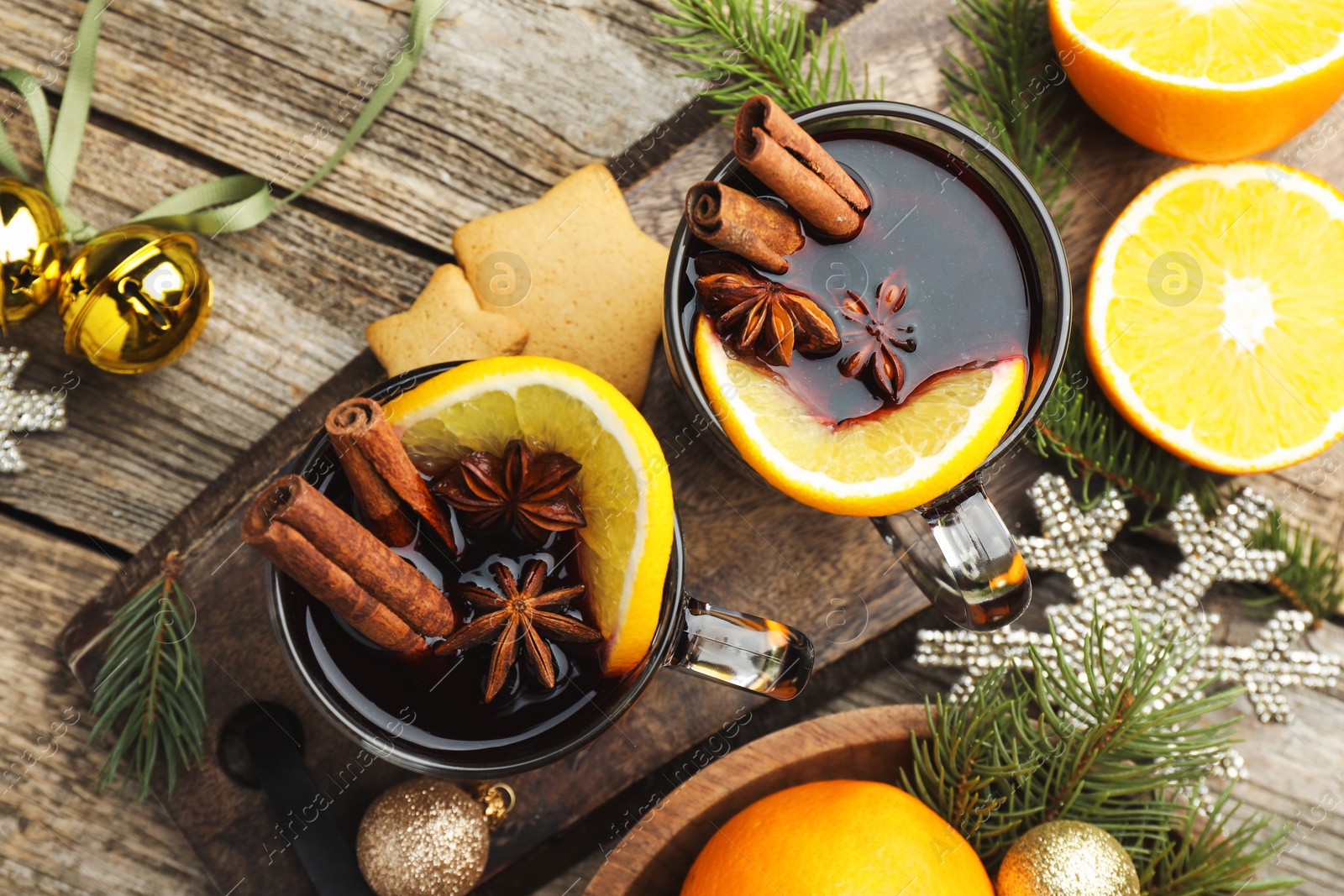 Photo of Tasty mulled wine with spices, orange slices, cookies and Christmas decor on wooden table, flat lay