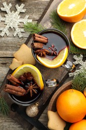 Photo of Tasty mulled wine with spices, orange slices, cookies and Christmas decor on wooden table, flat lay