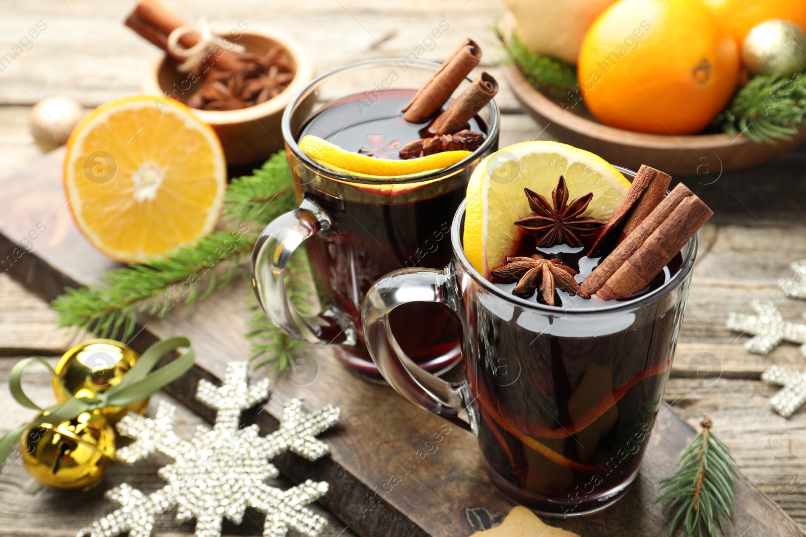 Photo of Tasty mulled wine with spices, orange slices and Christmas decor on wooden table, closeup