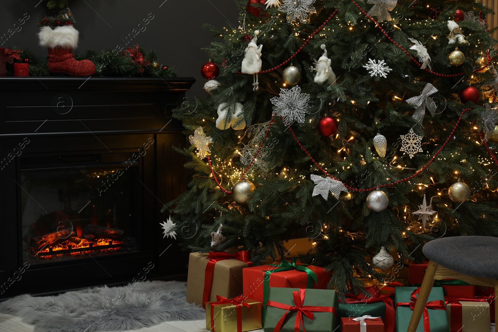 Photo of Christmas tree with festive decor, presents and fireplace in cozy room