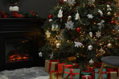 Photo of Christmas tree with festive decor, presents and fireplace in cozy room