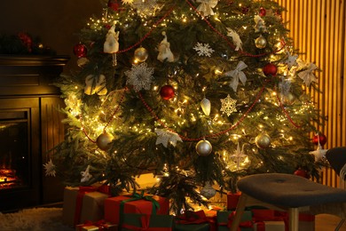 Photo of Christmas tree with festive decor, presents and fireplace in cozy room