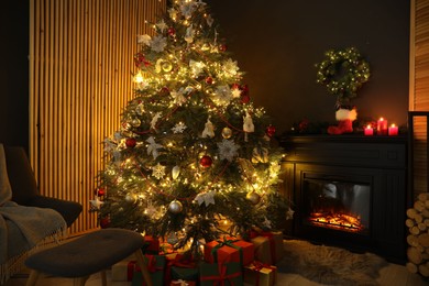 Photo of Christmas tree with festive decor, presents and fireplace in cozy room