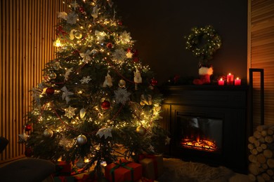 Photo of Christmas tree with festive decor, presents and fireplace in cozy room