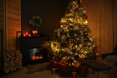 Photo of Stylish fireplace, Christmas tree with festive decor and presents indoors