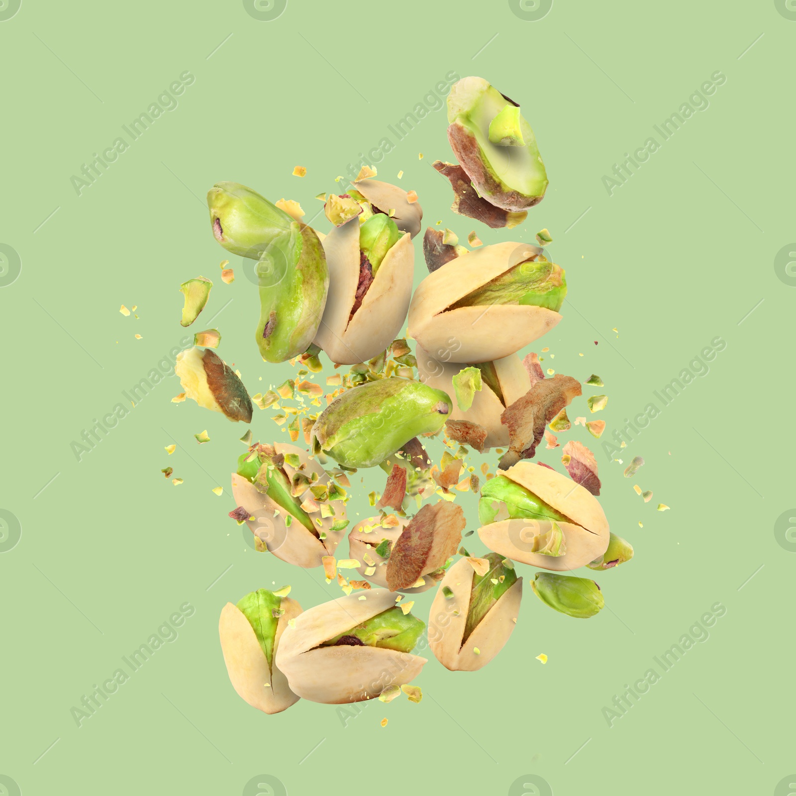 Image of Tasty pistachios with cracked nutshell in air on color background