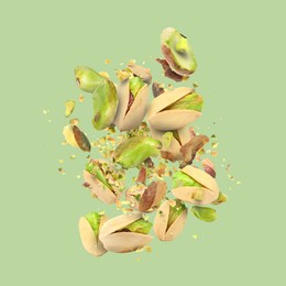 Image of Tasty pistachios with cracked nutshell in air on color background