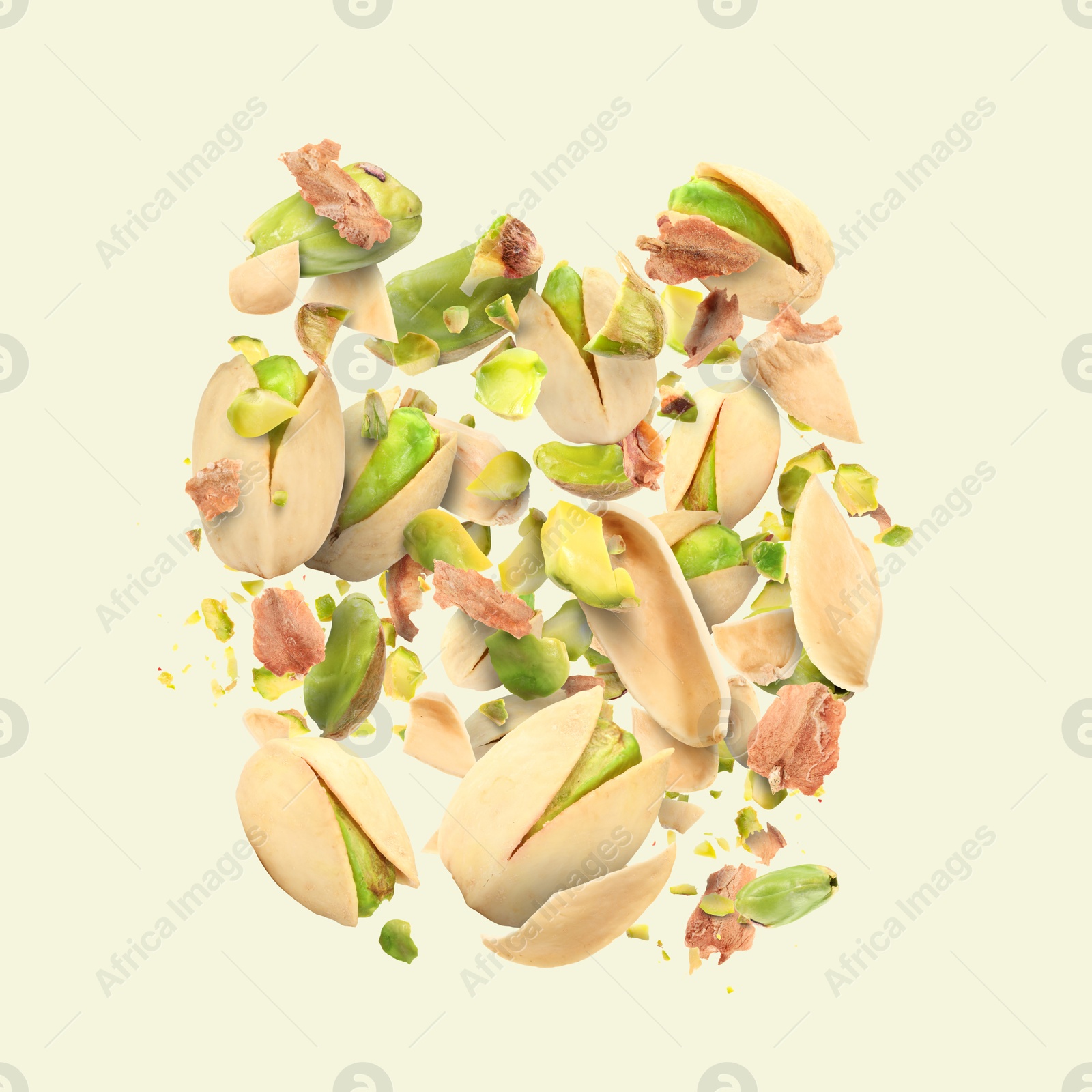 Image of Tasty pistachios with cracked nutshell in air on beige background