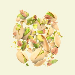 Image of Tasty pistachios with cracked nutshell in air on beige background