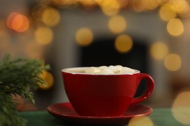 Photo of Tasty cocoa with marshmallows in cup and decor on table against blurred Christmas lights, closeup. Bokeh effect