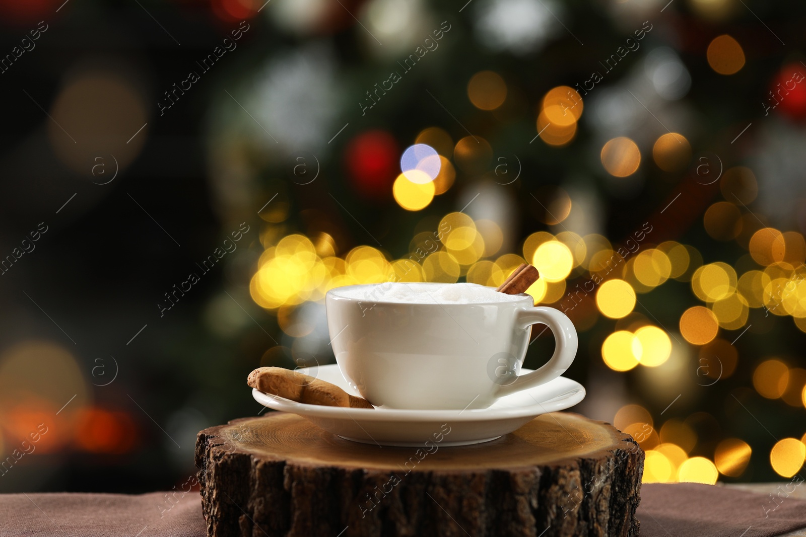 Photo of Aromatic coffee in cup and tasty cookie on table against blurred Christmas lights, bokeh effect