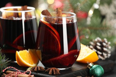 Photo of Tasty mulled wine with spices and Christmas decor on table, closeup