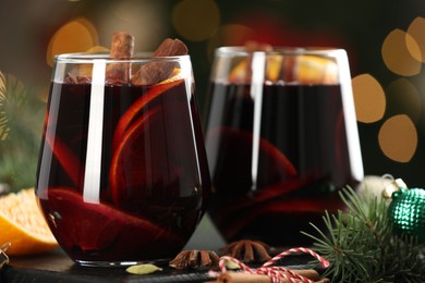 Photo of Tasty mulled wine with spices and decor on table against blurred Christmas lights, closeup. Bokeh effect