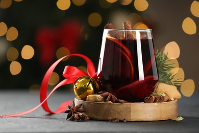 Photo of Tasty mulled wine with spices, cookies and decor on grey table against blurred Christmas lights, space for text. Bokeh effect