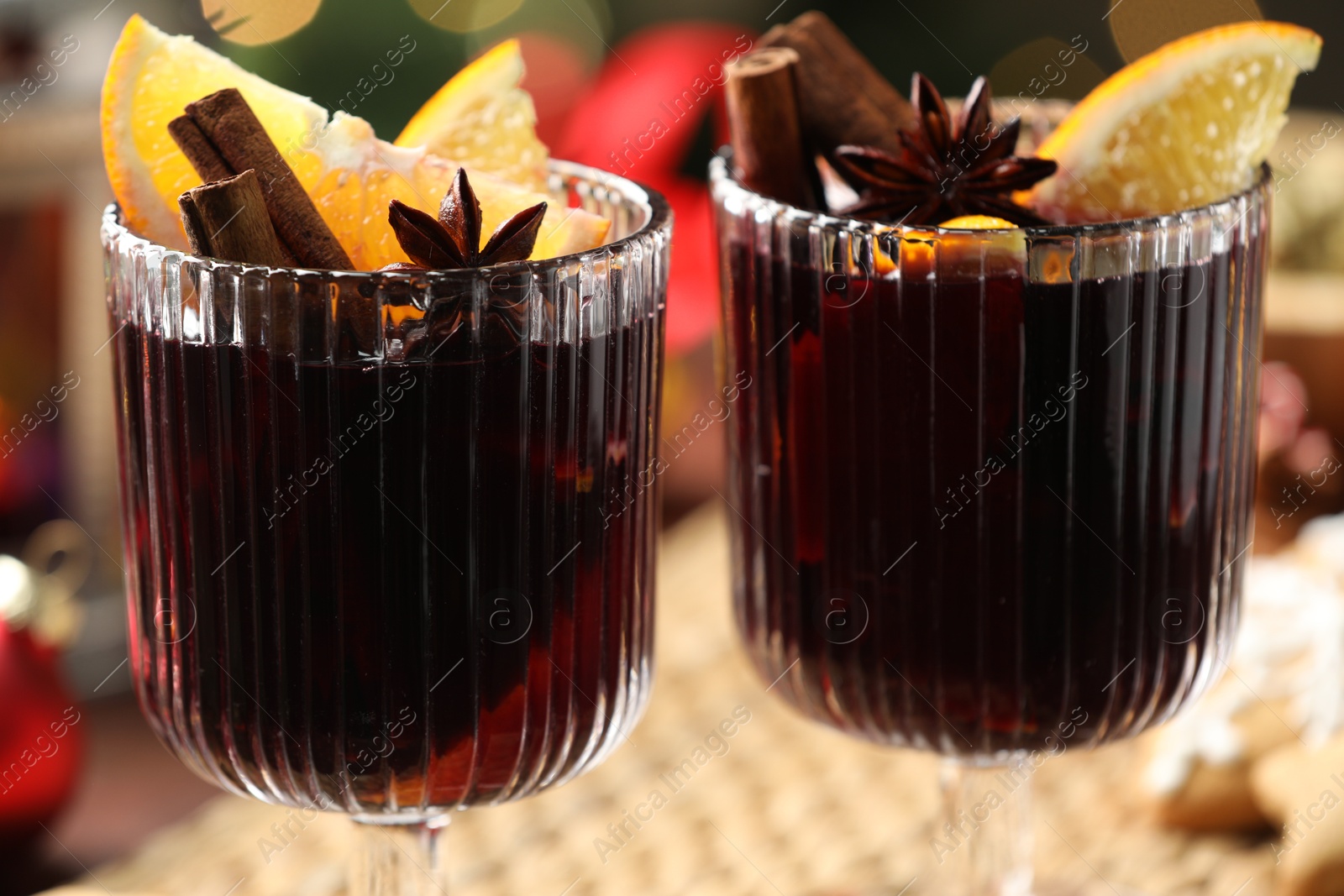 Photo of Tasty mulled wine with spices on blurred background, closeup. Christmas drink