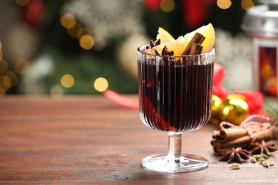 Photo of Tasty mulled wine with spices on wooden table against blurred Christmas lights, space for text. Bokeh effect