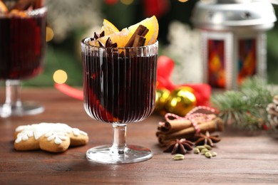 Photo of Tasty mulled wine with spices and Christmas decor on wooden table, closeup