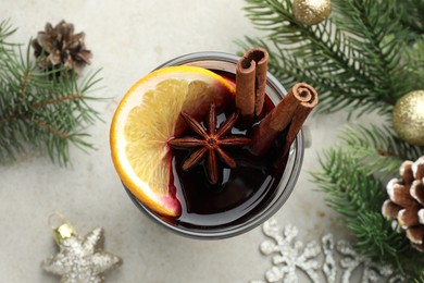 Photo of Tasty mulled wine with spices and Christmas decor on light grey table, flat lay