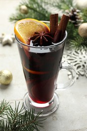 Photo of Tasty mulled wine with spices and Christmas decor on light grey table, closeup