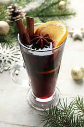 Photo of Tasty mulled wine with spices and Christmas decor on light grey table, closeup