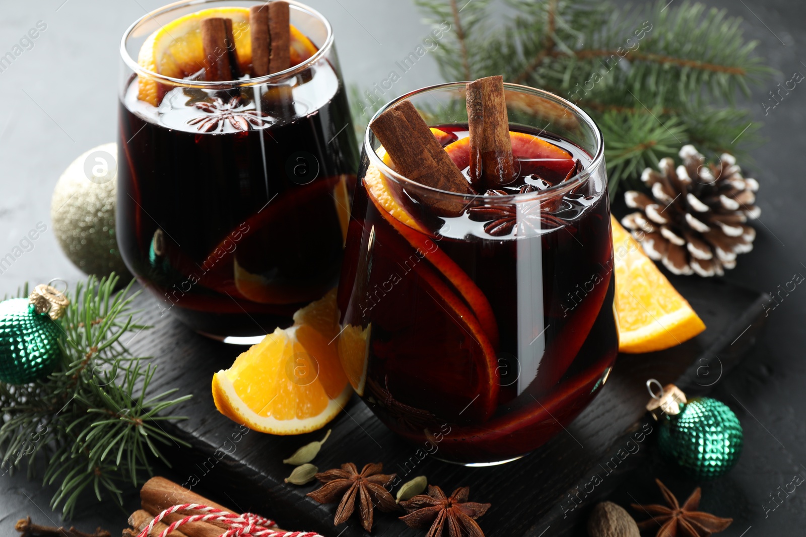 Photo of Tasty mulled wine with spices and Christmas decor on table, closeup