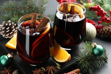 Photo of Tasty mulled wine with spices and Christmas decor on table, closeup