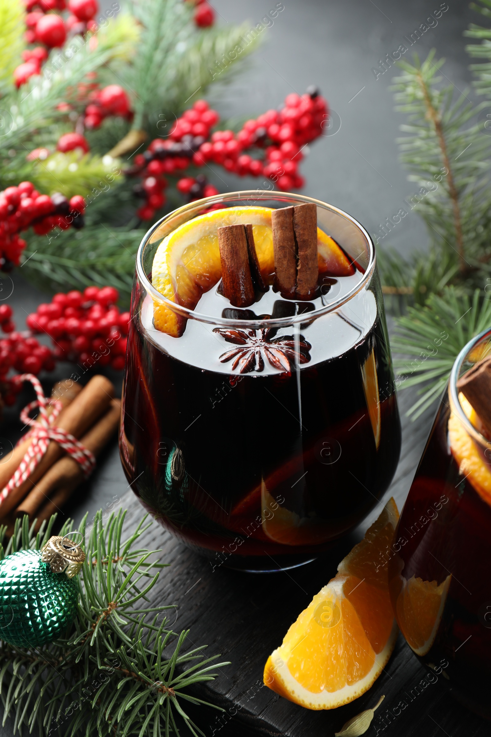 Photo of Tasty mulled wine with spices and Christmas decor on table, closeup