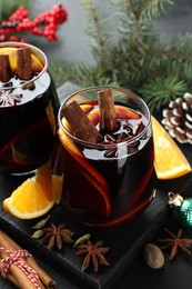 Photo of Tasty mulled wine with spices and Christmas decor on table, closeup