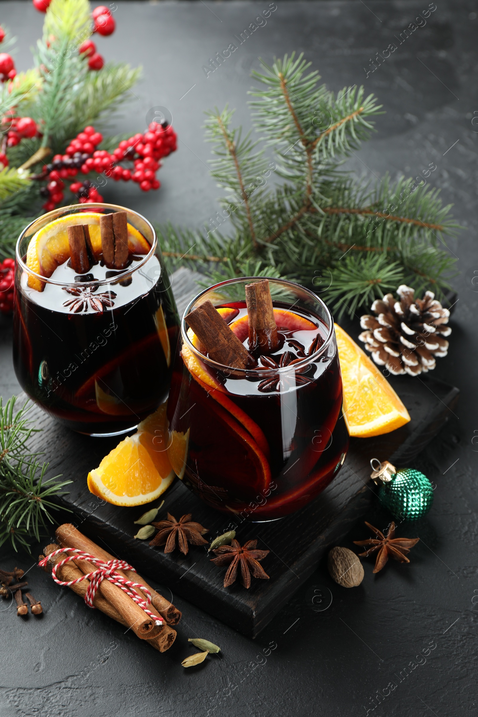 Photo of Tasty mulled wine with spices and Christmas decor on black table