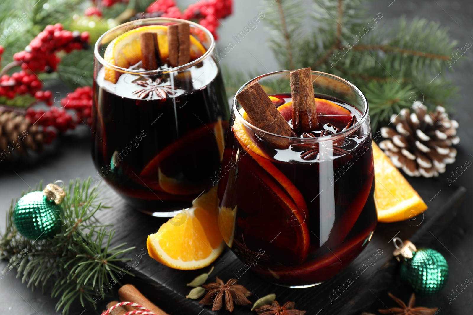 Photo of Tasty mulled wine with spices and Christmas decor on table, closeup