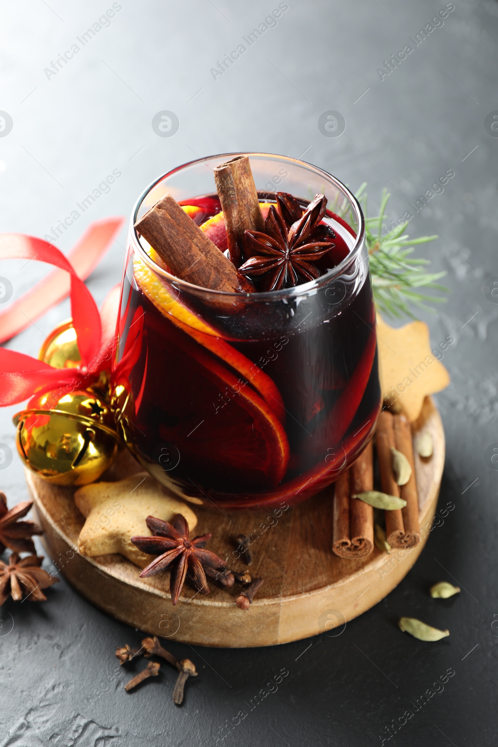 Photo of Tasty mulled wine with spices, cookies and Christmas decor on black table, closeup