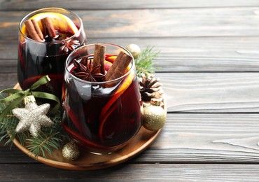 Photo of Tasty mulled wine with spices and Christmas decor on wooden table, closeup. Space for text