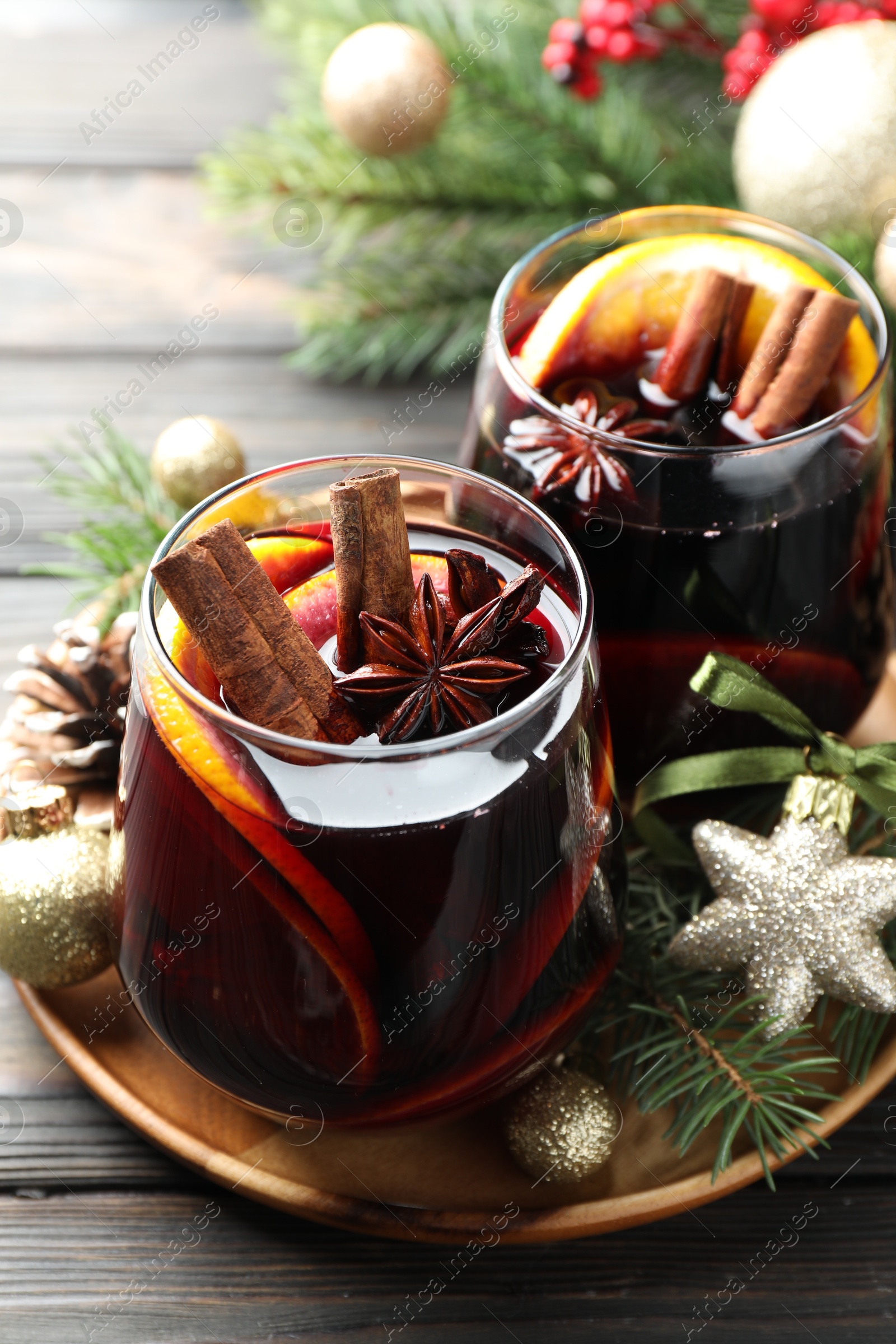 Photo of Tasty mulled wine with spices and Christmas decor on wooden table, closeup